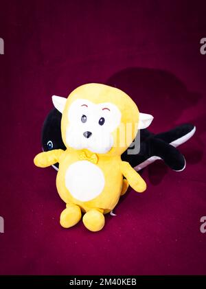 isolated yellow teddy with dark maroon background from front angle Stock Photo