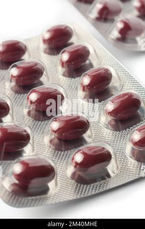 close-up of red iron tablets in blister packs, vitamin pills for improve iron level in blood, medical drug packages in selective focus on white Stock Photo