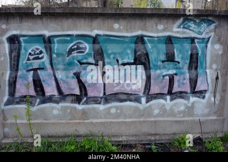 Graffiti blue, pink, purple words, written letters ARCHI. Graphic design made in a chaotic way when a paint can be washed on a concrete fence... Stock Photo