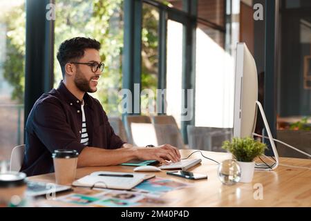I love my job. a handsome young businessman sitting alone in his office and typing on his computer. Stock Photo