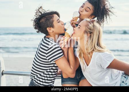 Here to spread some ice cream vibes. three friends eating ice while out on the promenade. Stock Photo