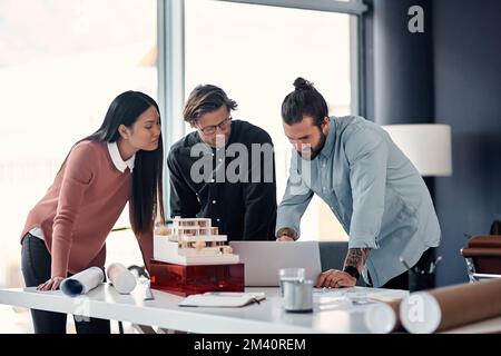 Three minds are always better than one. three young architects using a laptop while working together in their office. Stock Photo