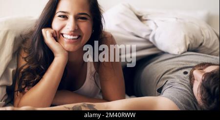 Make time to spend time. a happy young couple relaxing in bed together at home. Stock Photo