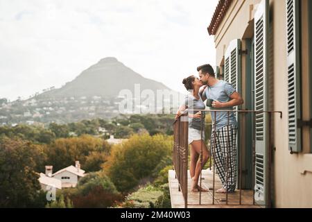 Love is beautiful. Full length shot of an affectionate young couple drinking coffee while standing on their balcony at home in the morning. Stock Photo