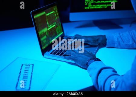 It only takes a few clicks to breach your firewall. an unrecognizable hacker using a laptop in the dark. Stock Photo