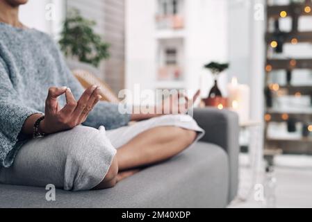 Youll never truly lose yourself. an unrecognizable woman meditating on a sofa at home. Stock Photo