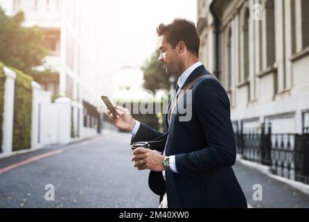 Im going to be late. a handsome young businessman texting on his cellphone while heading to work in the morning. Stock Photo