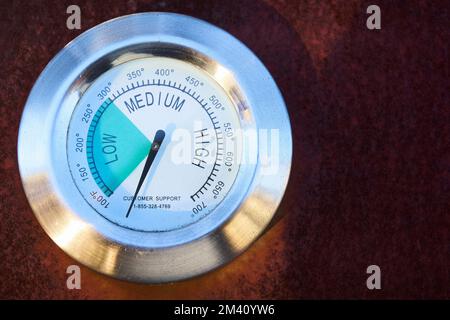 temperature gage on outside of BBQ grill. close up low medium high scale rust Stock Photo