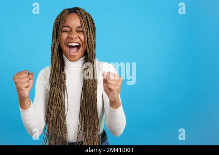 Happy african woman screaming as celebrating with fists up Stock Photo