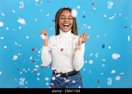 Excited African woman surrounded by flying confetti Stock Photo