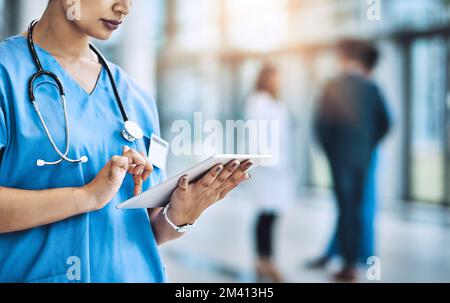Using the best apps to manage her tasks. a female nurse using a digital tablet. Stock Photo