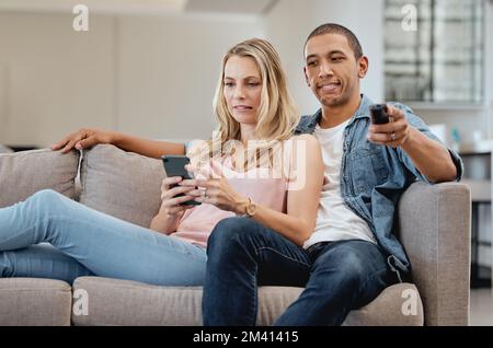 Curious, jealous and couple watching tv with a phone, social media and movie on living room sofa. Relax, jealousy and man reading communication on Stock Photo
