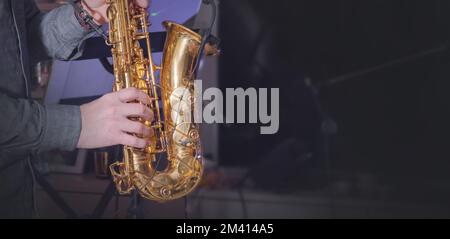 Hands of a man playing the saxophone. Dark background. Copy space Stock Photo