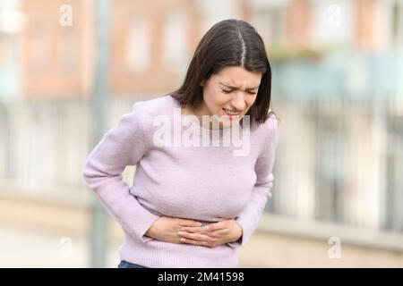 Teen suffering stomach ache in the street Stock Photo
