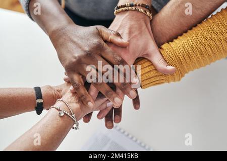 Were in this for the long run. a group of unrecognizable businesspeople joining hands together in solidarity inside their office at work. Stock Photo