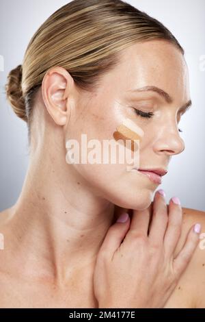 Makeup shade, cosmetics and face of a woman with foundation, facial cream and skincare on a grey studio background. Lotion, bb cream and cosmetic Stock Photo