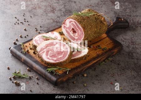 Pancetta is cured pork belly made with salt, herbs and spices closeup on the wooden board on the table. Horizontal Stock Photo