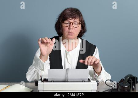 Retro office. Experienced secretary woman with glasses typing text on the old typewriter. At work. Stock Photo