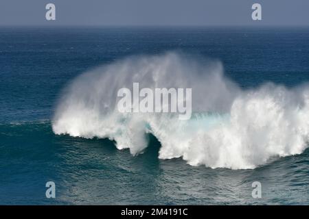 Beautiful high ocean waves in turquoise water. A wave is breaking with high spray. Stock Photo