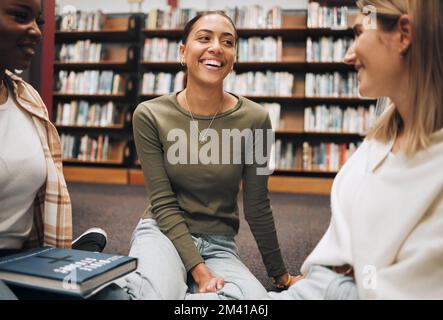 Student, friends and book discussion in library with smile for education, learning or knowledge at university. Group of happy women enjoy conversation Stock Photo