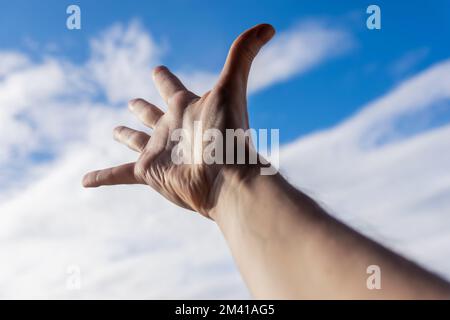 Hand of a man reaching to towards sky. Stock Photo