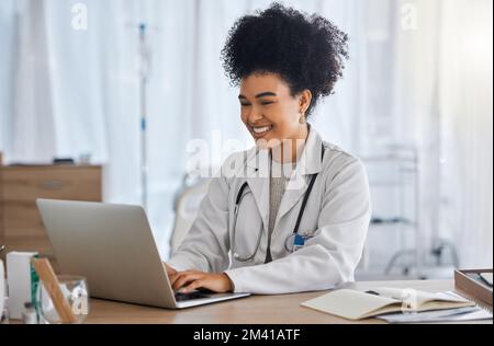 Black woman, doctor and laptop with smile for healthcare, email or telemedicine by work desk at the hospital. African American female medical expert Stock Photo