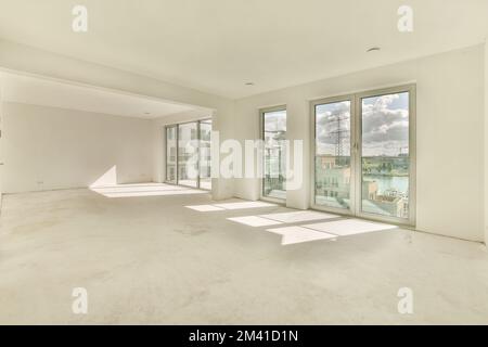 an empty living room with sliding glass doors leading out to the balcony and lake view in the distance is visible Stock Photo