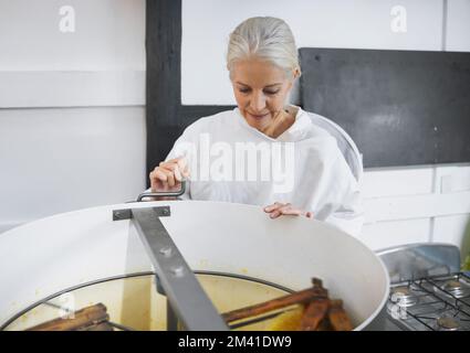 Beekeeper woman, factory and honey production with machine, focus and working in apiculture industry. Senior bee expert, harvesting process and Stock Photo