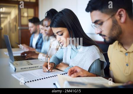 University, education and students studying for exam, test or assignment in the library on campus. Scholarship, knowledge and young friends learning Stock Photo