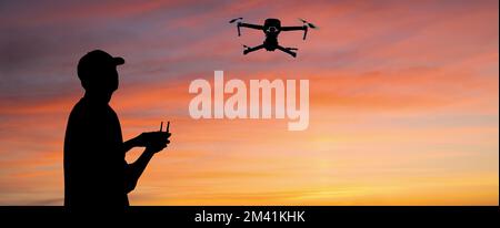 Silhouette of a man controls a drone on a sunset background Stock Photo