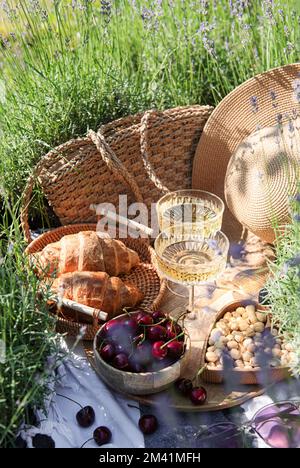 Summer picnic on a lavender field with champagne glasses and cherry berries Stock Photo