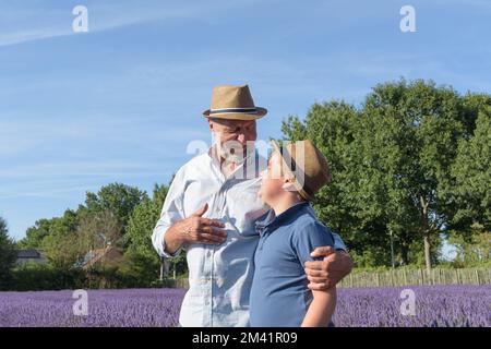 Portrait of grandfather and grandson walking in lavender field Stock Photo