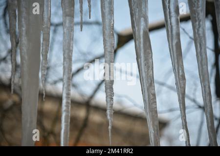 Icicles hanging from the roof against the sky Stock Photo