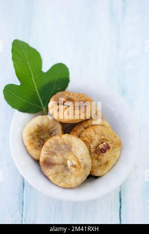 Delicious healthy dried figs with a fig tree leaf in a small bowl Stock Photo