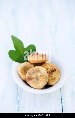 Delicious healthy dried figs with a fig tree leaf in a small bowl Stock Photo