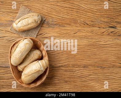 Whole grain french bread, salt bread or pistolet in a basket over wooden table with copy space. Stock Photo