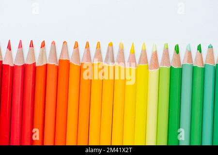 Raw of pencils paced in gradient from red to green over white background. Close up. Stock Photo