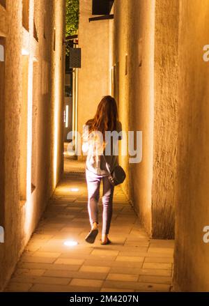 Young woman walks down the narrow street of Arabic village. Stock Photo