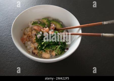 Bowl with salmon poke and chopsticks seen from above. Black background Stock Photo