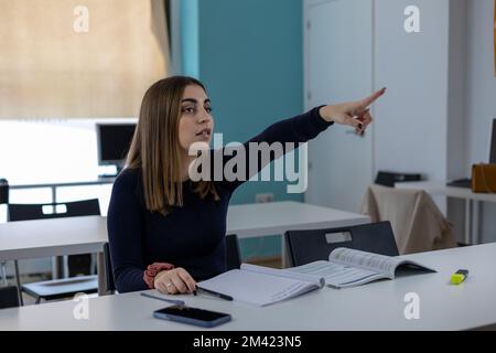 young woman student raising hand and asking question to professor during class in college Stock Photo