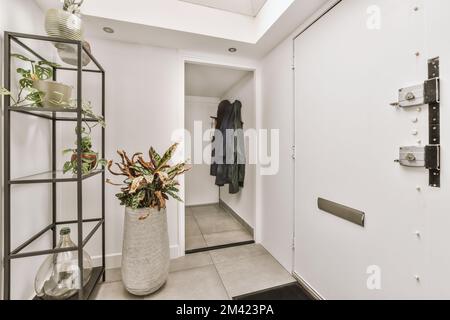 an entry way with plants in the vase and clothes hanging on the wall behind it, there is a coat rack next to the Stock Photo