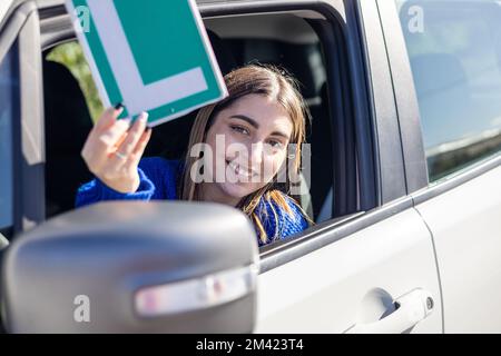 Happy young female driver showing her L sign lerner spain autoescuela Stock Photo