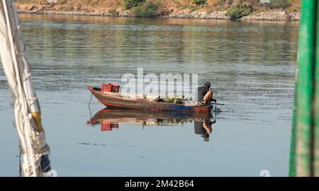 Traditional egyptian bedouin fisherman in rowing boat on river Nile fishing by riverbank Stock Photo