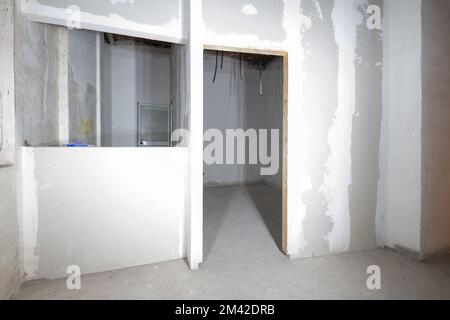 Raw room with plasterboard walls in a renovated building and corrugated plastic pipes for conducting electrical cables Stock Photo