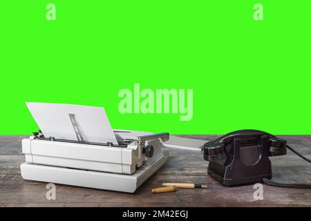 Typewriter, old telephone, ink pen and notepad on a textured table. Green screen. Chroma Key Stock Photo