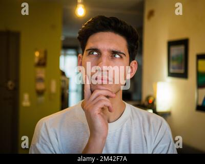 Dubious, unsure handsome young man thinking, at home Stock Photo