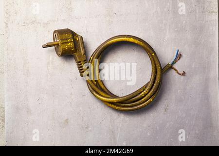 a used and broken power outlet with its wires neatly coiled lying on the floor Stock Photo