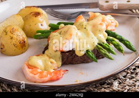 Delicious Steak Oscar with jumbo prawns served with roasted potatoes. Stock Photo