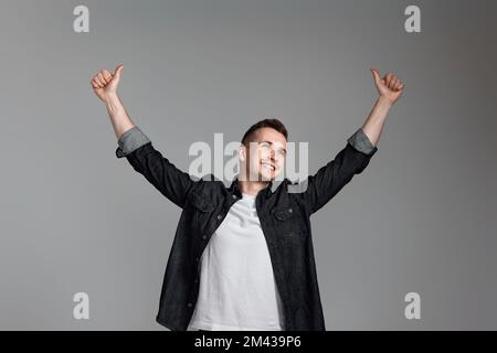 amazed man celebrating victory on gray background. Stock Photo