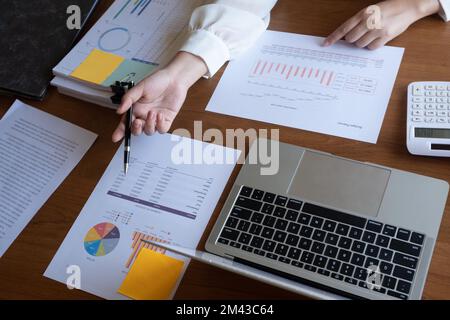 Cropped image of professional businesswoman, entrepreneur or accountant working on a financial report paperwork at her desk, using calculator, laptop Stock Photo